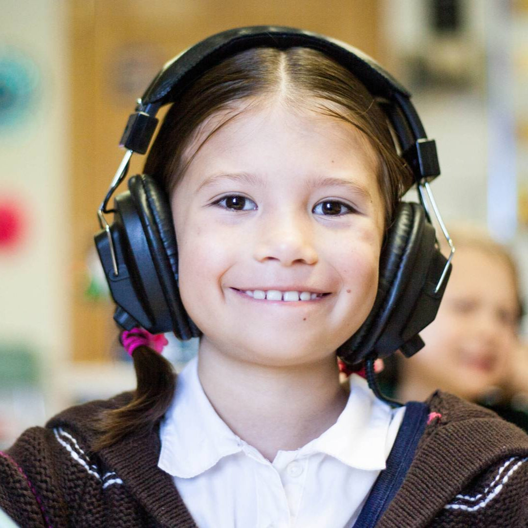 Young girl wearing large headphones in a classroom setting