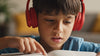 Close up on young dyslexic boy with headphones reading a book slowly using his finger to trace the words